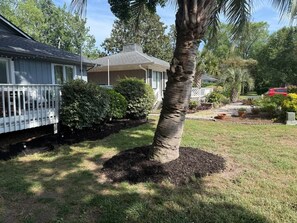 A residential property with a house, a fenced yard, a palm tree, and a garden with various plants and a red car. - Palmetto Safari Retreat (Horry County)