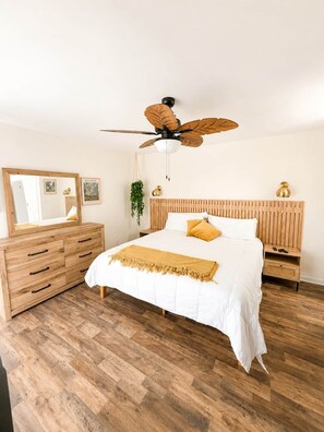 A bedroom with a wooden bed, a wooden dresser, a ceiling fan, and a mirror. - Palmetto Safari Retreat (Horry County)