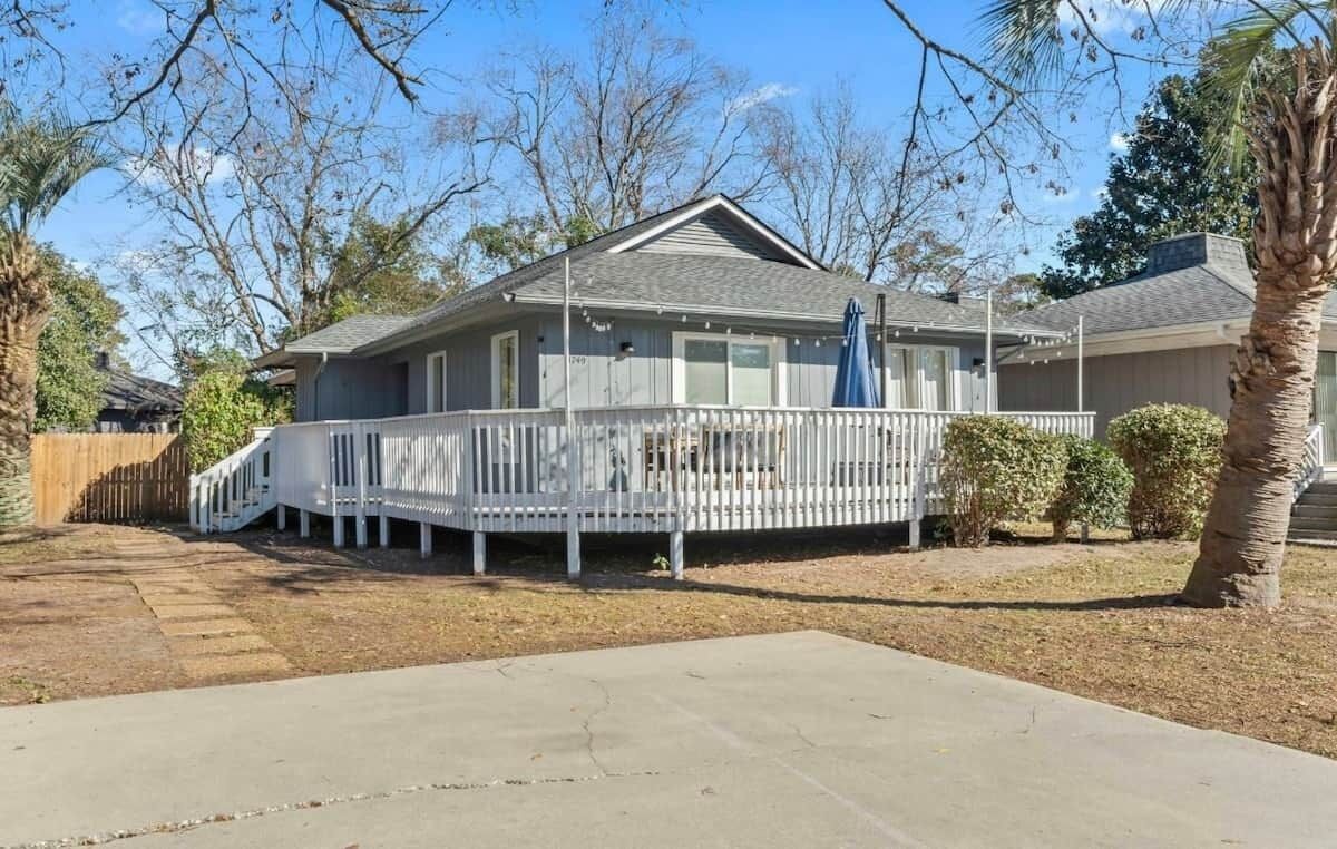 Einbungalow mit überdachter Veranda und umzäuntem Garten.