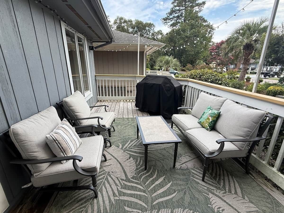An outdoor patio with two sofas, a small table, and a grill.
