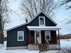 A two-story house with a front porch, a chimney, and a visible number '113' on the door. - Quaint City Cottage just minutes from Killington (Rutland)