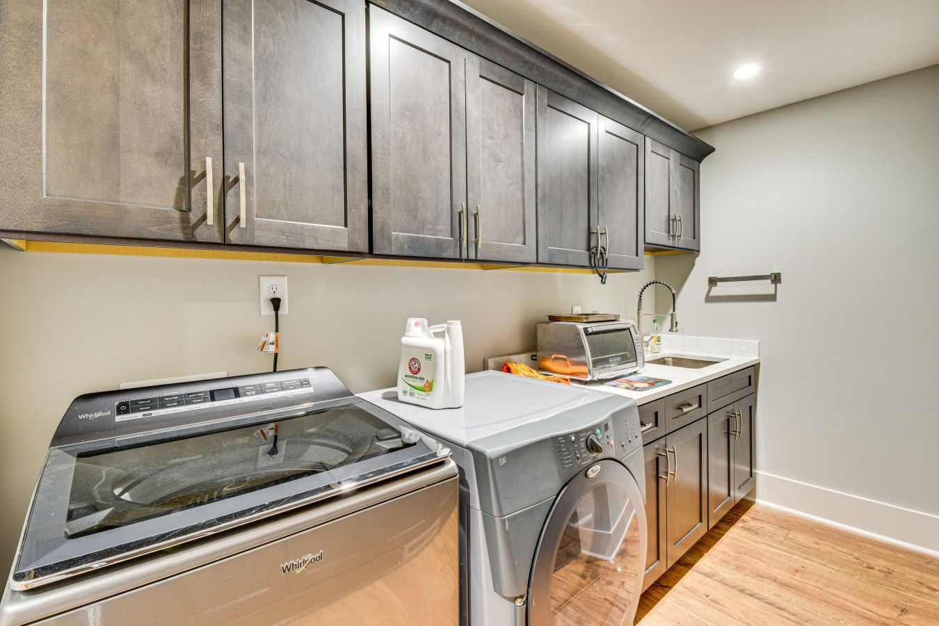 Una cocina con lavadora Whirlpool, una encimera con tostadora y un fregadero.