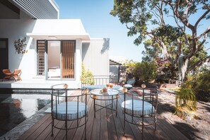 A modern outdoor patio with a pool, seating, and a tree. - Villa Camilla | Private Pool & Serenity | Saint-Pierre • Reunion Island (Saint-Pierre)