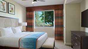 Ein Hotelzimmer mit Bett, Schreibtisch, Stuhl, Fernseher und einem Fenster mit Vorhängen.