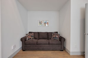 A room with a brown sofa, two patterned throw pillows, and two abstract art pieces on the wall. - 3BR Nashville Retreat Near Downtown & Five Points (Nashville)