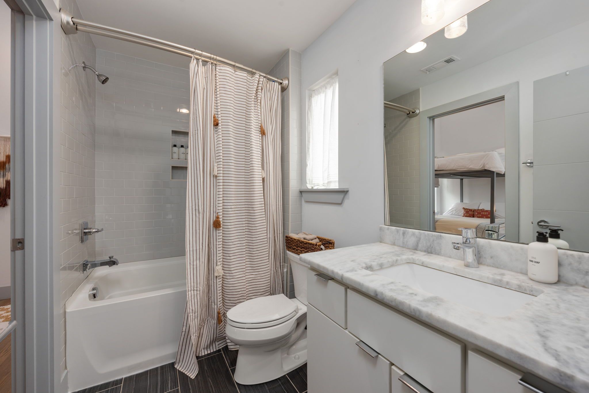 A modern bathroom with a bathtub, toilet, and a vanity with a mirror.
