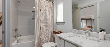 A modern bathroom with a bathtub, toilet, and a vanity with a mirror.