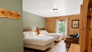 Une chambre avec deux lits, un banc en bois et une tête de lit en bois.
