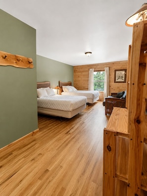 A bedroom with two beds, a wooden bench, and a wooden headboard. - Alaska Legends Kenai River Lodge (Soldotna)