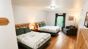 Une chambre avec deux lits, un plancher en bois, une fenêtre avec des rideaux et une chaise.