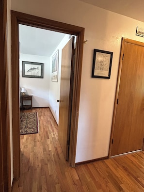 A hallway with wooden flooring, a door, and framed pictures on the wall. - Bright & Cozy 2 BR 1 BA house, fenced & pet friendly, garage & driveway parking. (Yakima)