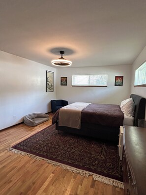 Une chambre à coucher avec un lit, un tapis, une chaise et un luminaire au plafond.