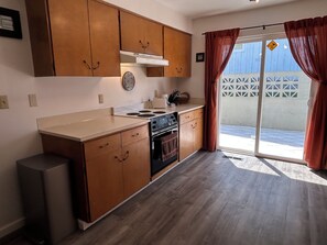 Une cuisine dotée de meubles en bois, d’une cuisinière et d’une grande porte-fenêtre coulissante donnant sur un espace extérieur.