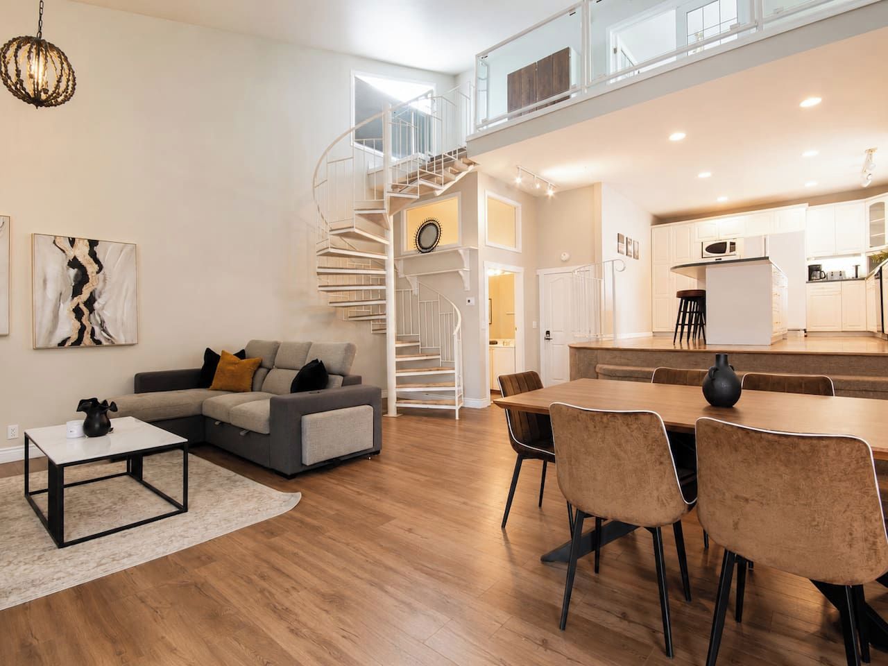 Un salon moderne avec un escalier en colimaçon, un coin repas et une cuisine.
