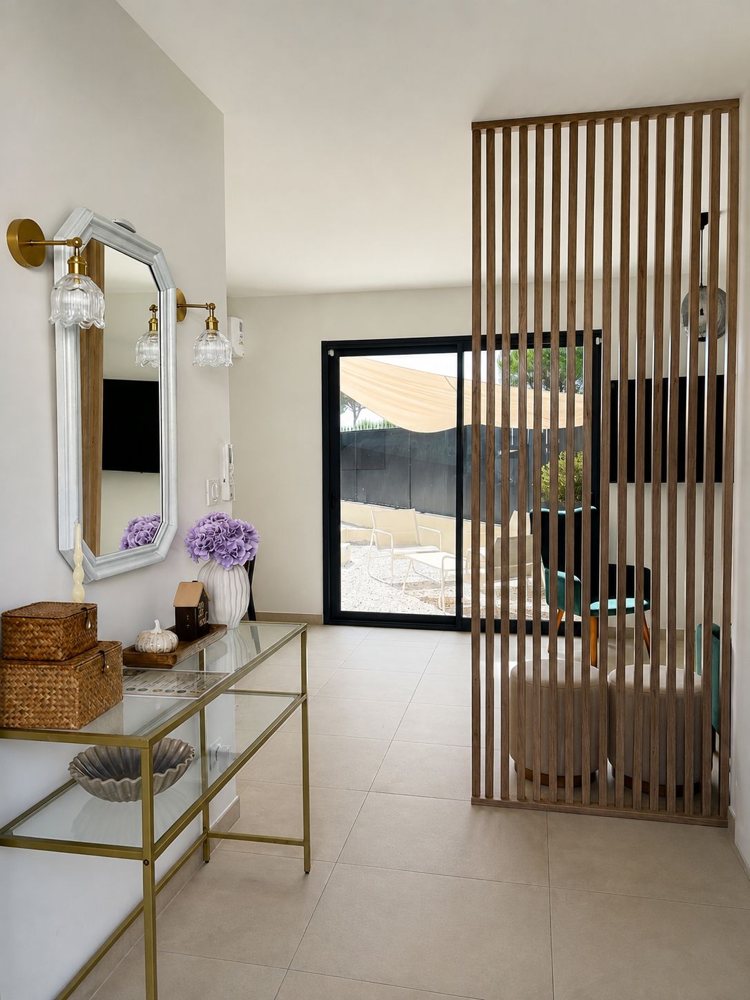 A modern interior with a glass console table, a large mirror, and a wooden partition.