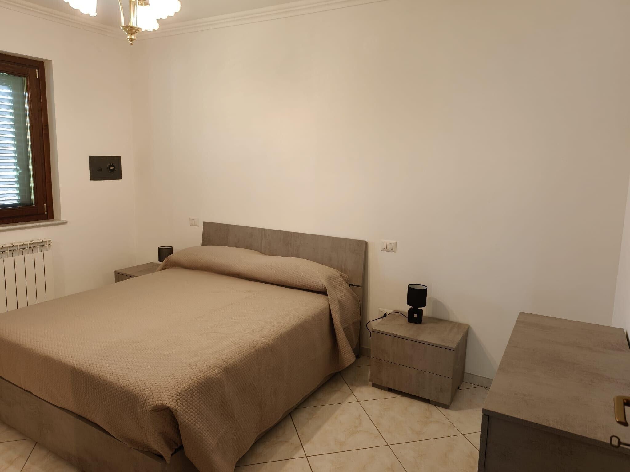 A bedroom with a bed, bedside tables, a nightstand, and a radiator.