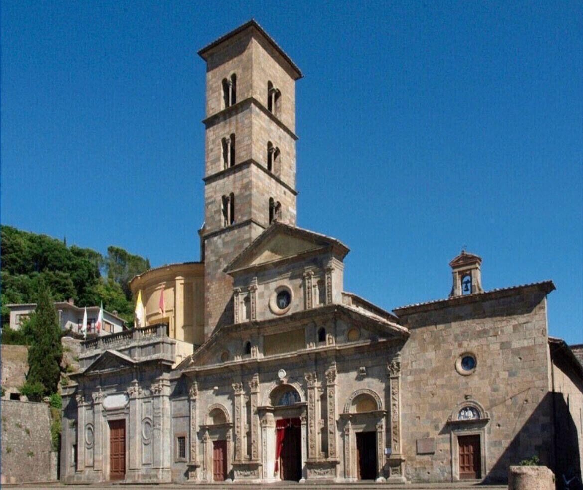 A historic church with a prominent bell tower, a main entrance with a red door, and a smaller building attached to the main structure.