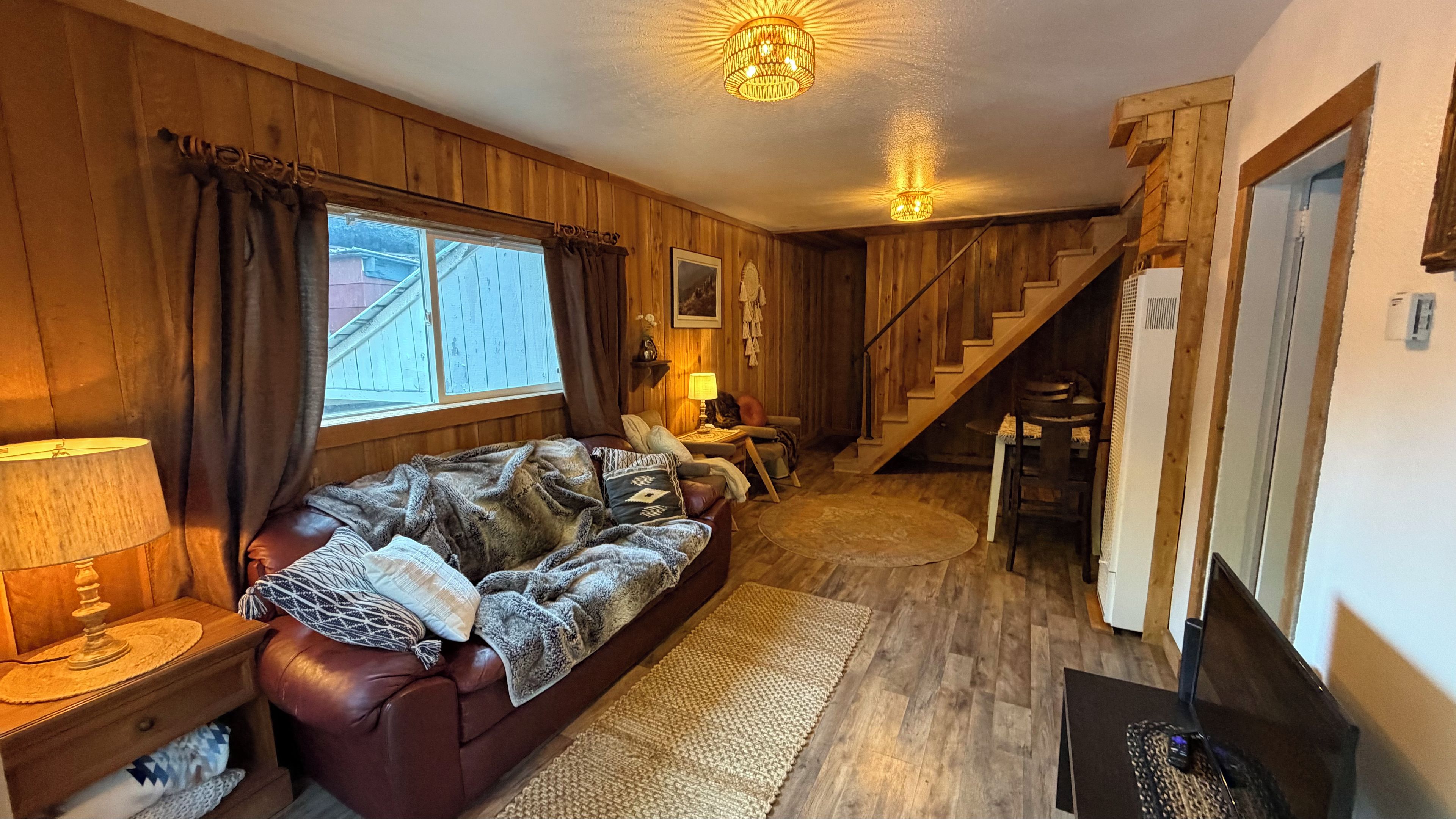 A cozy room with a sofa, a lamp, a rug, and a staircase leading to another area.