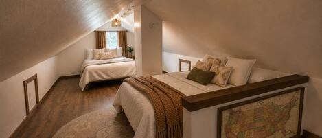 Une chambre avec un grand lit, un plus petit lit, un tapis rond, une carte accrochée au mur et un luminaire au plafond.