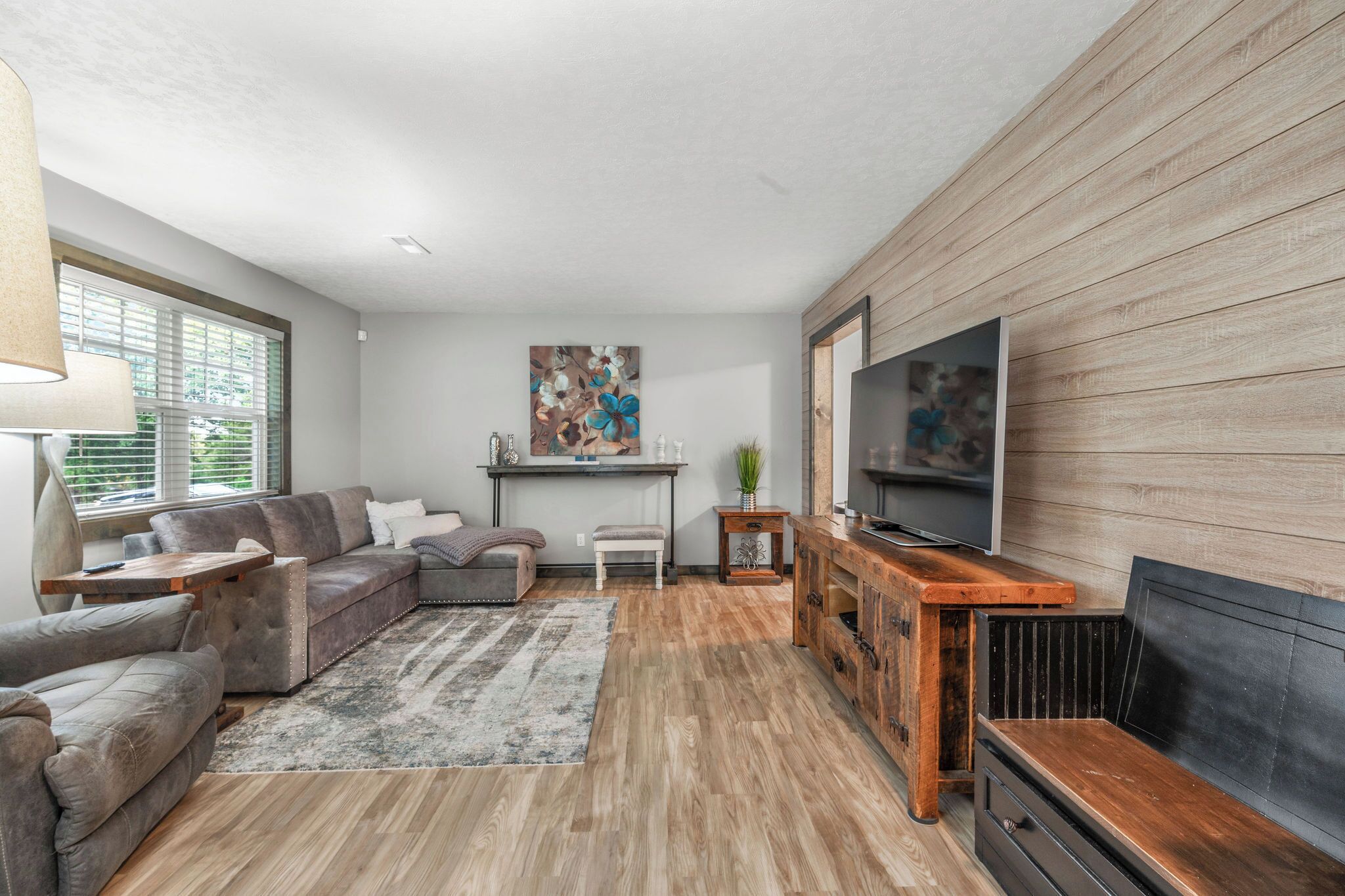 A modern living room with a sectional sofa, a coffee table, a fireplace, and a television.