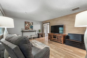 A modern living room with a grey sofa, wooden flooring, a flat-screen TV, and a fireplace. - Traveling professionals ideal space in Ozark (Ozark)