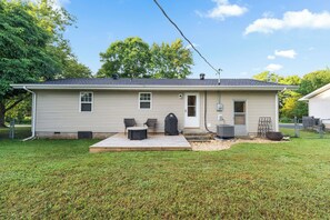 Une maison de plain-pied avec un patio couvert, une porte et un petit garage attenant.