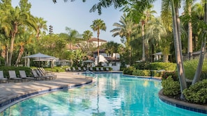 Una piscina rodeada de palmeras y sillas de descanso.