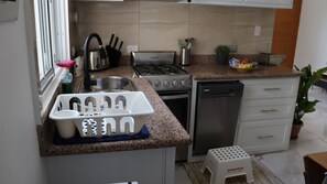 A compact kitchen with a gas stove, sink, and a dishwasher. - CasaMIA RD: Your Caribbean Getaway. (Río San Juan)
