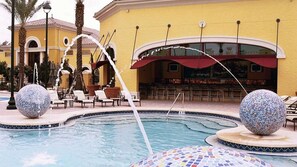 Ein Poolbereich mit Liegestühlen, einer Bar und dekorativen Kugeln.