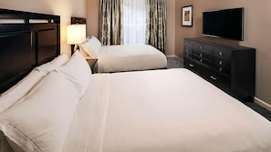 Ein Hotelzimmer mit einem großen Bett, einem Schminktisch, einem Fernseher und Vorhängen.