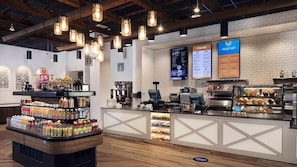 Ein Café-Interieur mit Theke, Getränkeauslage, Speisekarten und einer Ziegelwand.