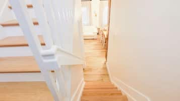 Uma escadaria leva a um quarto com uma cama e uma mesa de cabeceira.