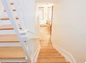 A staircase leading to a room with a bed and a nightstand.
