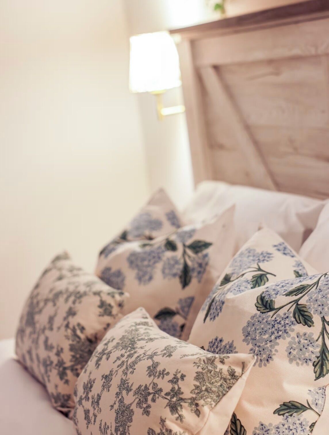 A bed with floral-patterned pillows and a wooden headboard.