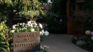 Un letrero de madera con el texto 'WELCOME TO SALVESTRIN EST. 1932' frente a un edificio con balcón.