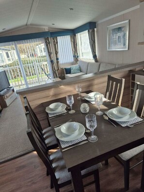 A dining area with a wooden table set for four, surrounded by chairs. - Cala Gran Holiday Park - Holiday Accommodation 20084 (Fleetwood)