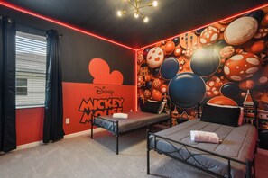 A Mickey Mouse-themed room with two beds, a window with black curtains, and a wall mural of Mickey Mouse and other characters. - Special Offer! Near Disney/Theater/Game Rooms/Private SPA 2425 (Kissimmee)