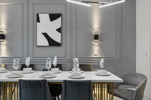 A modern dining room with a long table set for six, featuring white plates, bowls, and glassware. - Special Offer! Near Disney/Theater/Game Rooms/Private SPA 2425 (Kissimmee)