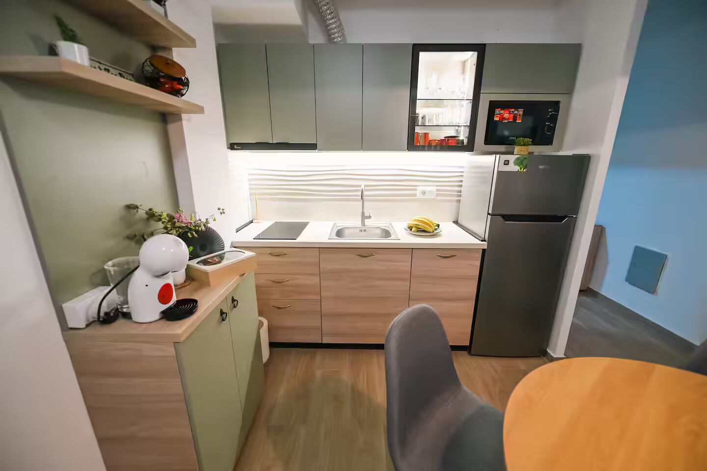 A modern kitchen with a built-in microwave, a refrigerator, and a sink.