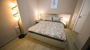 Een slaapkamer met een bed, bedlampjes, een wandlamp en een deur.