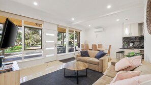 A modern living room with a sofa, coffee table, and TV. - Unit 2 PI Holiday Retreat (Cowes)