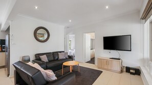 A modern living room with a sofa, coffee table, and a flat-screen TV.