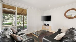 A modern living room with a large window, a flat-screen TV, a glass coffee table, and leather sofas. - PI Holiday Retreat in Chapel Street (Cowes)