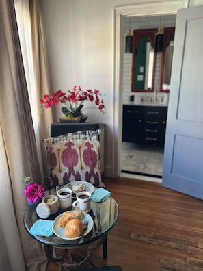 A dining area with a table set for breakfast, including croissants and coffee, and a view into the kitchen. - Romantic & Comfortable Studio in Historic Burns Square with Central Air & Heat (Sarasota)