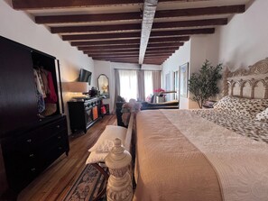 Une chambre à coucher avec un lit, une commode, un miroir et une fenêtre avec des rideaux.