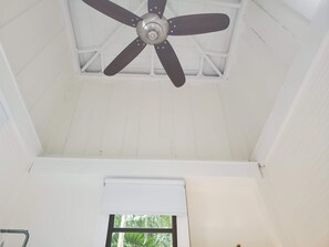 Ein Deckenventilator in einem Zimmer mit weißen Wänden und einem Fenster.