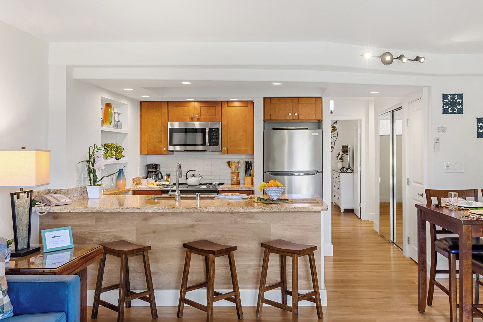 Una cocina moderna con armarios de madera, electrodomésticos de acero inoxidable y una isla central con taburetes.