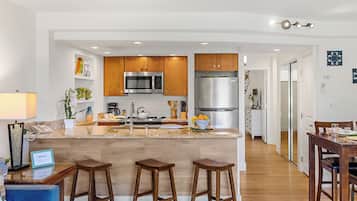 Una cocina moderna con armarios de madera, electrodomésticos de acero inoxidable y una isla central con taburetes.