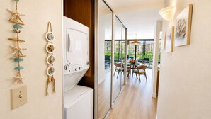 Una camera d'albergo con lavatrice, un'area pranzo con tavolo e sedie, e vista esterna.