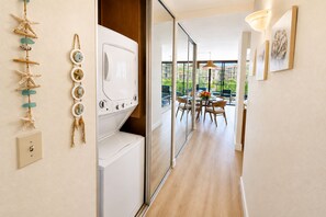 Quarto de hotel com máquina de lavar roupa, área de refeições com mesa e cadeiras, e vista para o exterior.